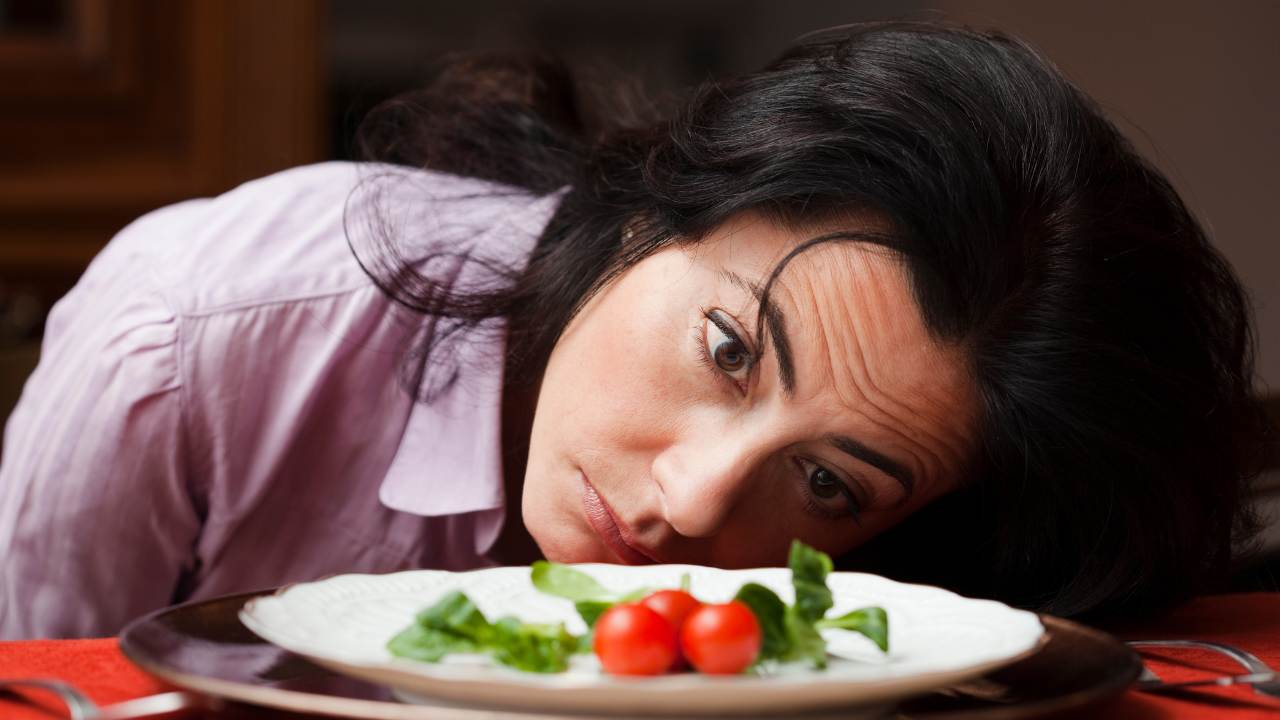 Lady staring at a small salad on a plate demonstrating portion control for reversing type 2 diabetes