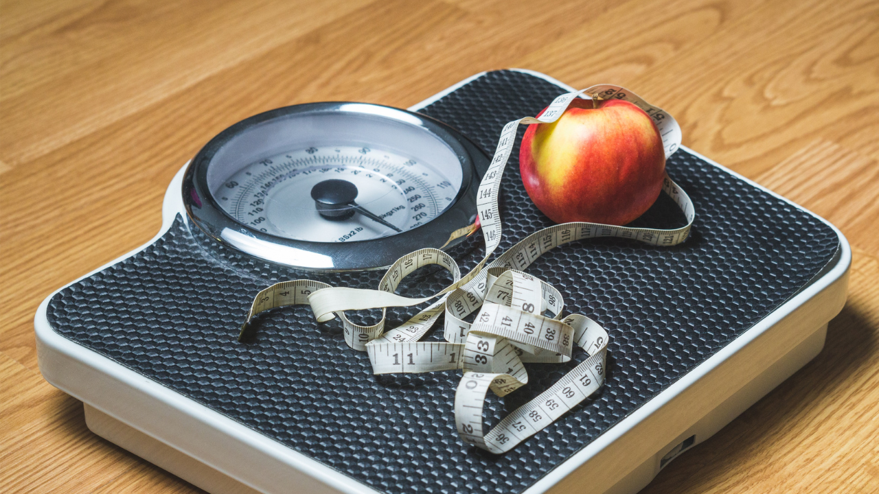 Apple on weighing scales representing healthy food choices for blood sugar control and reversing type 2 diabetes