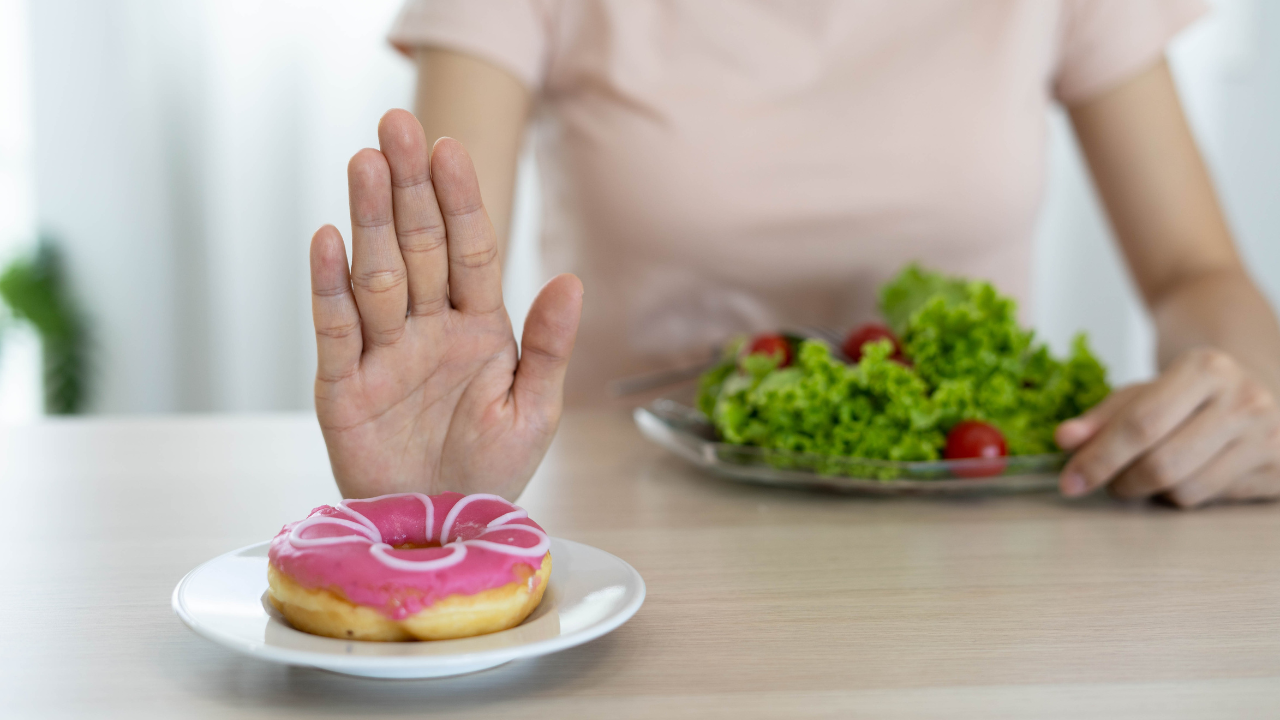 A hand rejecting a doughnut in favour of a healthy salad, symbolising smart food choices for reversing type 2 diabetes