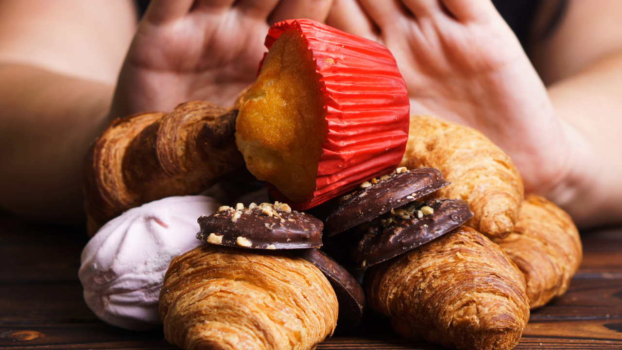 Hands pushing away pastries and junk food to illustrate mindful eating and blood sugar control