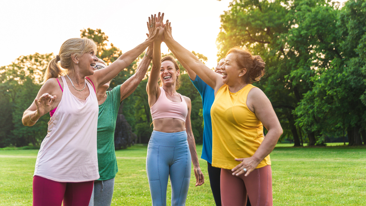 Five people exercising outdoors, high-fiving, promoting connection and group health coaching for reversing type 2 diabetes
