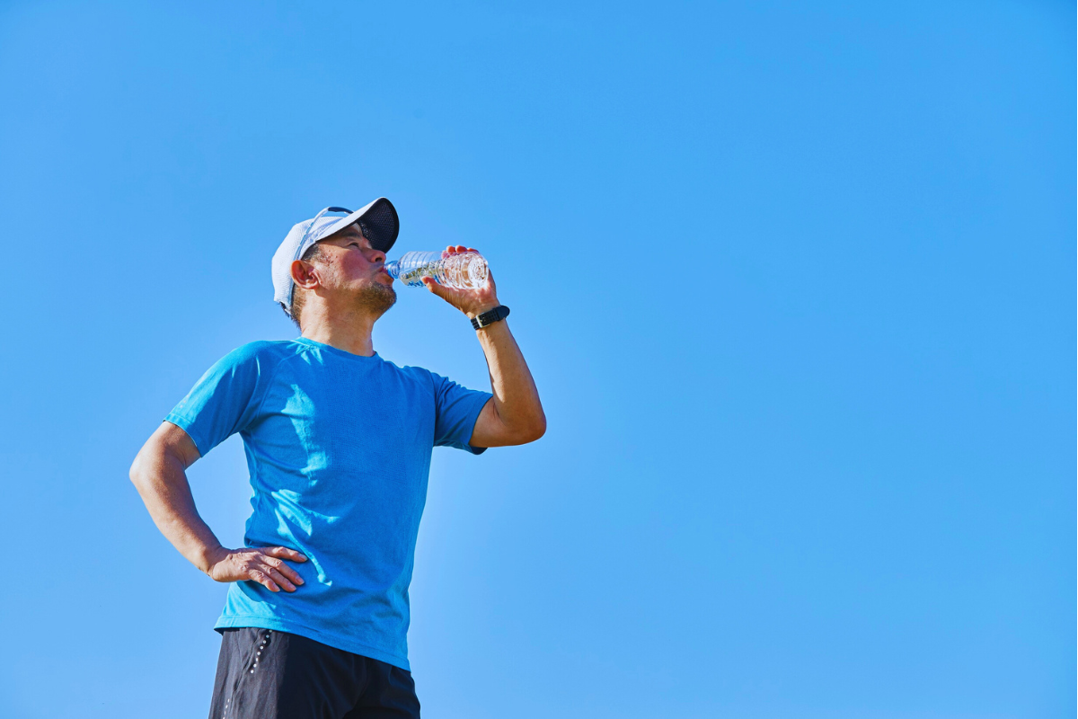 Man drinking a bottle of water outdoors for hydration and blood sugar control