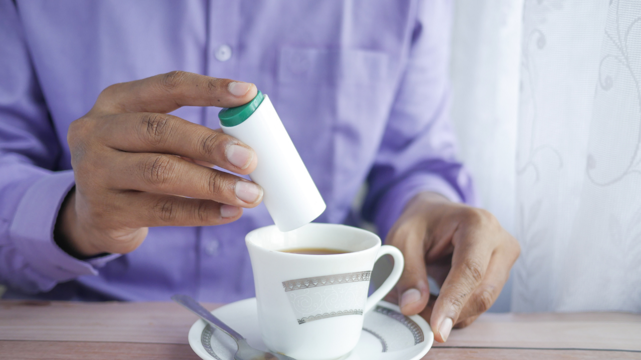 Person adding artificial sweetener to a cup of tea